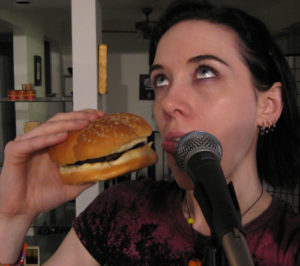 Me with my mouth between a burger and a mic, sticking my tongue out like it's such a burden to want those things